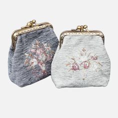 two purses with embroidered flowers on the front and back, one in grey and one in white