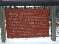 a red sign that is on the side of a wooden fence with snow around it