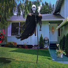 a house decorated for halloween with a ghost on it's front porch and lawn