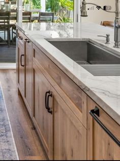 a kitchen with marble counter tops and wooden cabinets in front of a dining room table