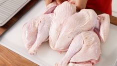 a person cutting up raw chicken on a cutting board