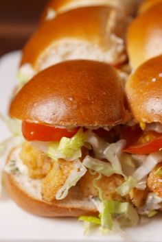 two sandwiches with chicken, lettuce and tomato on them sitting on a white plate