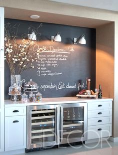 a kitchen with a chalkboard on the wall and wine bottles in front of it