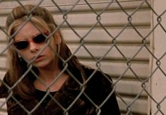 a woman wearing sunglasses behind a chain link fence