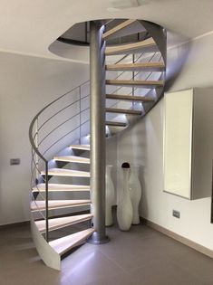 there is a spiral staircase in the middle of this room with vases on the floor