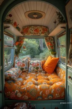 the inside of an rv with floral curtains and pillows on it's windowsill