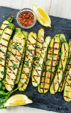 grilled zucchini on a slate platter with lemon wedges and seasoning