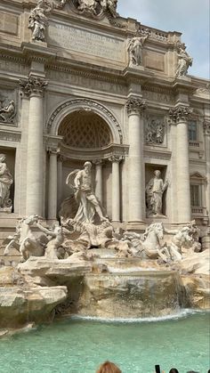 people are standing in front of a fountain