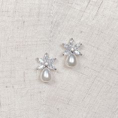 pair of pearl and crystal earrings on white fabric