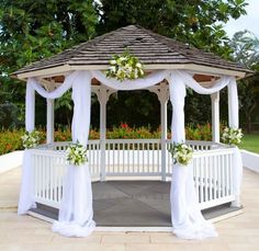 a gazebo decorated with white flowers and greenery