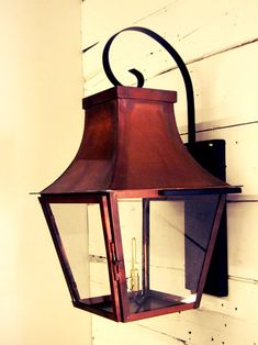 an old fashioned lantern hanging on the side of a wall with a candle in it