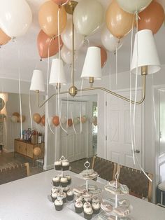 cupcakes and muffins on a table in a room with balloons hanging from the ceiling