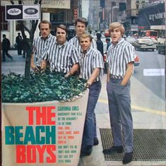 the beach boys are standing in front of a large planter with plants growing out of it