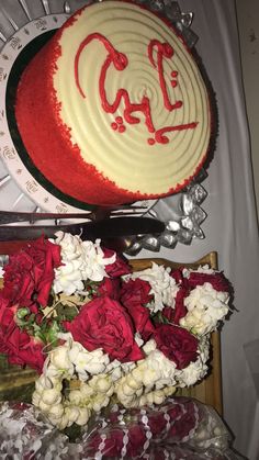 red and white flowers are in front of a cake with the word cali on it