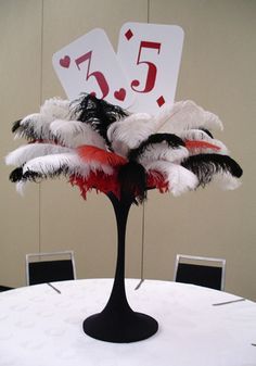 a table topped with a tall vase filled with feathers and cards on top of it