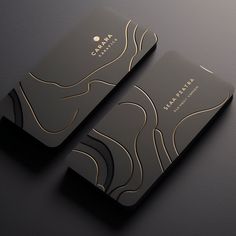 two black business cards with gold foil designs on the front and back of each card