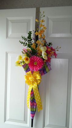 a bouquet of flowers hanging on the front door with polka dot ribbon tied around it