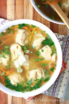 a bowl of soup with dumplings, carrots and parsley on the side