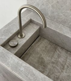 a bathroom sink with a metal faucet and marble counter top in the corner