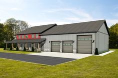 a large garage with two cars parked in front of it on top of a grass covered field