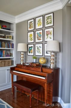 a living room with a grand piano in the center and several framed pictures on the wall