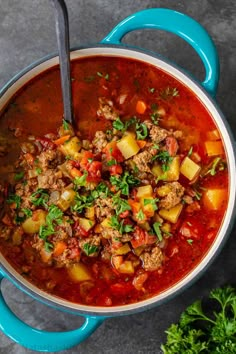 a blue pot filled with meat and vegetables next to some parsley on the side