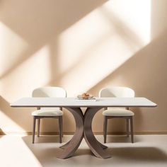 a white table with four chairs and a plate on it in front of a wall