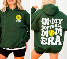 a woman wearing a green softball hoodie with the words in my softball mom bra on it