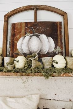 white pumpkins and gourds are sitting on the mantle