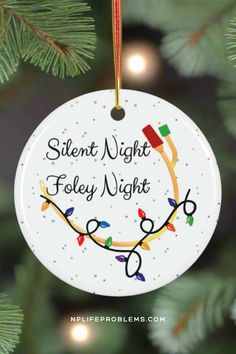 a white ornament hanging from a christmas tree with the words silent night, folksy night