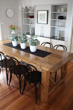 a dining room table with chairs and potted plants