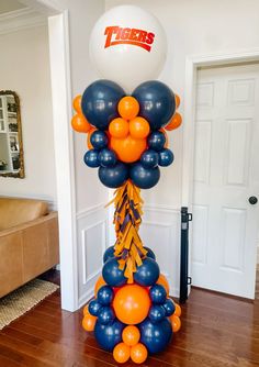 an orange, blue and black balloon tower is in the middle of a living room