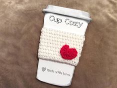 a cup cozy with two hearts attached to it on top of a brown bed sheet