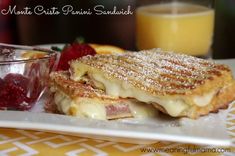 a white plate topped with french toast and fruit next to a glass of orange juice