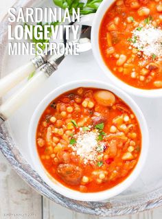 two white bowls filled with soup and topped with parmesan cheese