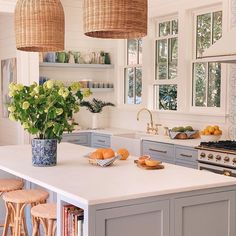 a kitchen with an island, sink and several hanging lights over it's windows