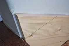 the corner of a room with wood flooring next to a white wall and door