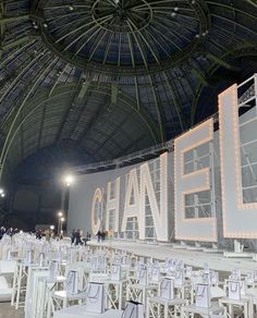 the chanel logo is lit up in front of rows of white tables and chairs