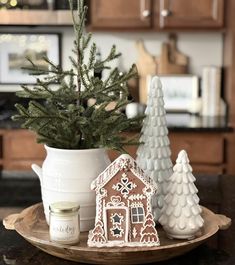 a small christmas tree in a pot next to two gingerbread houses on a plate