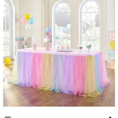 an image of a table set up for a party with colorful tulle skirts and balloons