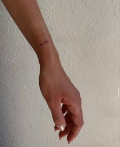 a woman's hand with a small tattoo on it and the word love written across her left wrist