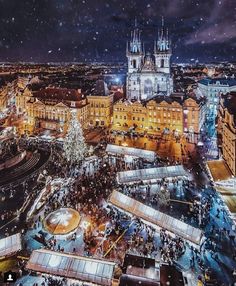 an aerial view of the christmas market in prague at night with lights and people walking around