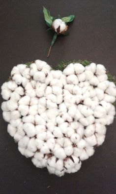 cotton balls arranged in the shape of a heart on a black surface with green leaves