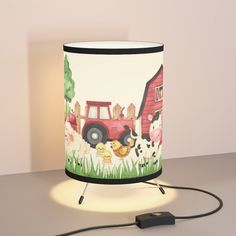 a lamp that has a farm scene on it and is lit up with a plugged in charger