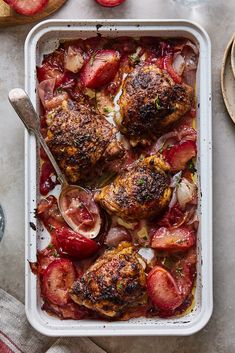 a pan filled with meat and vegetables on top of a table next to utensils