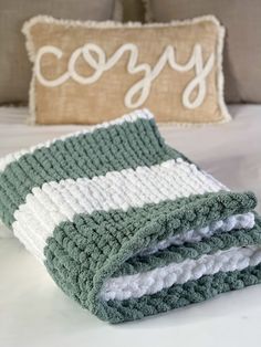 two crocheted blankets sitting on top of a bed next to a decorative pillow