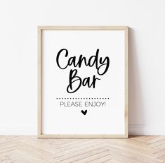 a sign that says candy bar please enjoy in black ink on a white wall next to a wooden frame