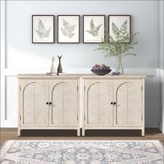 the sideboard is painted white and has three framed pictures above it, along with a bowl of fruit