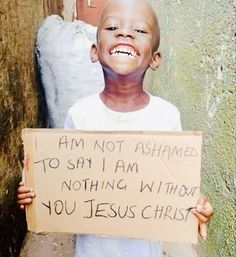 a young boy holding a sign that says i am not ashamed to say i am nothing without you jesus christ