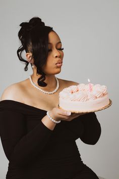 a woman holding a cake with a candle on it